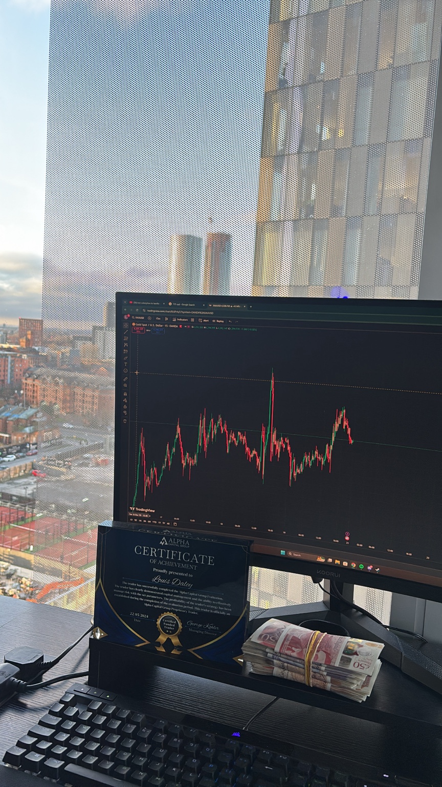 Louis Daley's trading desk with a live chart and funded trader certificate